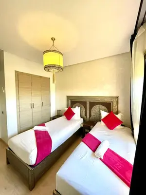 two beds in a room with red and white pillows at Prestihia jade in Marrakech