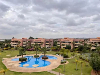 an apartment complex with a large pool in a park at Prestihia jade in Marrakech