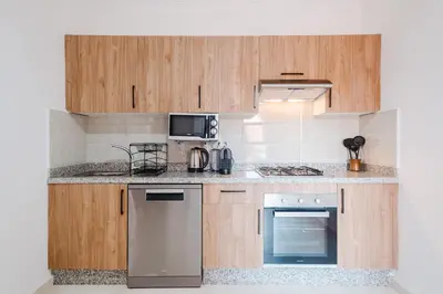 a kitchen with wooden cabinets and stainless steel appliances at Charming Apartment Guéliz Pool-Parking 24h-7j Security 10 a pied de M Avenue in Marrakech