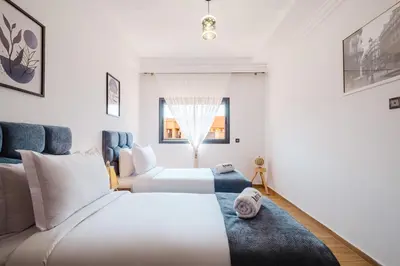 a bedroom with two beds and a couch at Charming Apartment Guéliz Pool-Parking 24h-7j Security 10 a pied de M Avenue in Marrakech