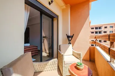 a balcony with a couch and a chair and a table at Charming Apartment Guéliz Pool-Parking 24h-7j Security 10 a pied de M Avenue in Marrakech