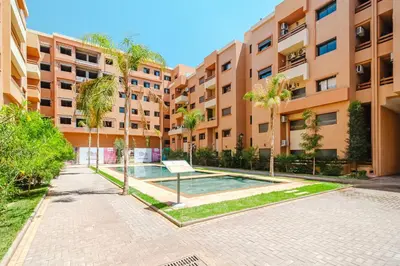 an apartment complex with a swimming pool in front of a building at Charming Apartment Guéliz Pool-Parking 24h-7j Security 10 a pied de M Avenue in Marrakech