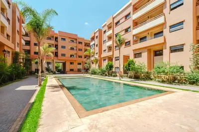an apartment complex with a swimming pool in front of a building at Charming Apartment Guéliz Pool-Parking 24h-7j Security 10 a pied de M Avenue in Marrakech