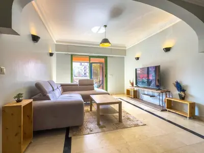 a living room with a couch and a tv at Majorelle Cozy Apartment Garden 2-Balcony Downtown in Marrakech