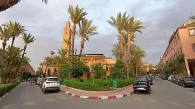 a street with cars parked in a parking lot with palm trees at Riad Four Rooms & Pool in Marrakech