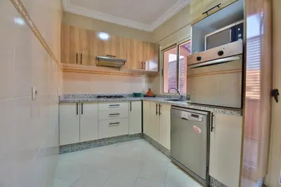 a kitchen with wooden cabinets and a dishwasher at Appartement Les Huit Palmiers in Marrakech