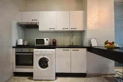 a kitchen with a washing machine and white cabinets at Central location-Queensize bed- Parking, AC & Iptv in Marrakech