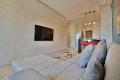 a living room with a white couch and a tv at Central location-Queensize bed- Parking, AC & Iptv in Marrakech