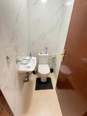 a white bathroom with a toilet and a sink at Appartement La Palmeraie Marrakech in Marrakech
