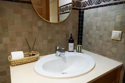 a bathroom sink with a bottle of wine and a mirror at Peaceful 2BR Oasis with Pool Tennis AC - Palmeraie in Marrakech