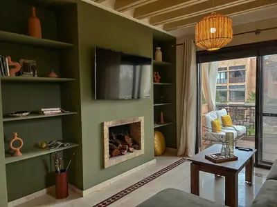 a living room with a fireplace and a flat screen tv at Peaceful 2BR Oasis with Pool Tennis AC - Palmeraie in Marrakech