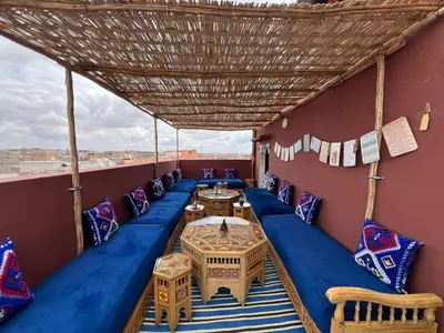 a balcony with a blue couch and tables and chairs at Dar ESSEKIA in Marrakech