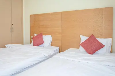 two white beds with red pillows in a room at Bel appartement vue sur piscine, fibre optique, parking gratuit in Marrakech