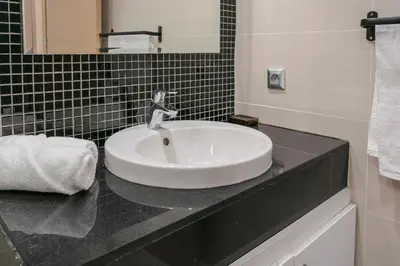a bathroom sink with a faucet on a counter at Bel appartement vue sur piscine, fibre optique, parking gratuit in Marrakech