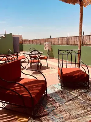 a patio with two beds and a table and chairs at Appartement cosy au coeur des souks de Marrakech in Marrakech