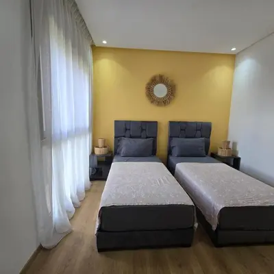 a bedroom with two beds and a mirror on the wall at Luxury Flat 2 Bedrooms Prestigia Golf City in Marrakech