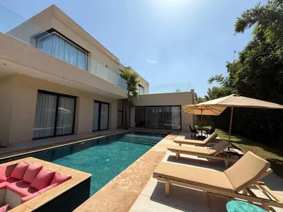 a house with a swimming pool with chairs and umbrellas at Modern Villa Selma in Marrakech