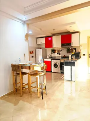 a kitchen with red cabinets and a wooden table at Appartement cosy Marrakech in Marrakech