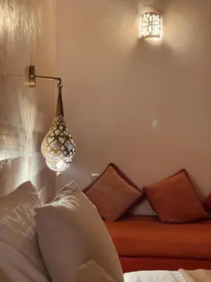 a room with a bed with a lamp and pillows at Momo House- Riad Momo in Marrakech