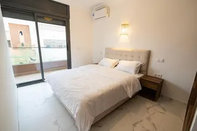 a white bed in a room with a large window at Jawhar Appart A4 in Marrakech