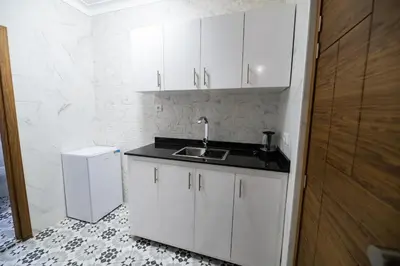 a white kitchen with a sink and a refrigerator at Jawhar Appart A4 in Marrakech