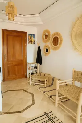 a living room with rattan chairs and a wooden door at Appartement Cosy Majorelle au Centre-Ville - Netflix-Fibre in Marrakech