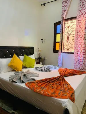 a bed with an orange blanket on top of it at Dar béa in Marrakech