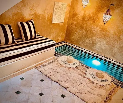 a room with a pool with a bench and a table at Riad Kimee Room 3 in Marrakech