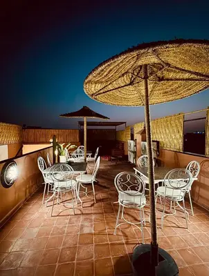 a patio with tables and chairs and an umbrella at Riad Kimee Room 3 in Marrakech