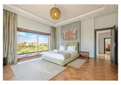a bedroom with a bed and a large window at Villa Pivoine avec Jacuzzi, Cuisinière, Piscine in Marrakech
