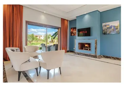 a living room with a table and chairs and a fireplace at Villa Pivoine avec Jacuzzi, Cuisinière, Piscine in Marrakech