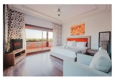 a hotel room with a bed and a television at Villa Magnolia avec Jacuzzi, Cuisinière, Piscine in Marrakech