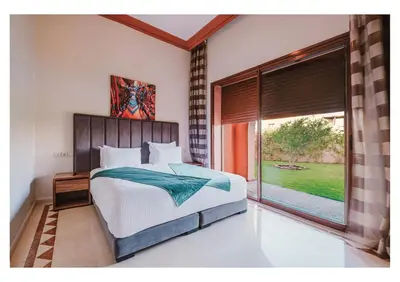 a bedroom with a bed and a large window at Villa Magnolia avec Jacuzzi, Cuisinière, Piscine in Marrakech