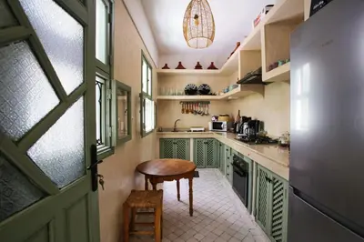 a kitchen with green cabinets and a wooden table at Riad Akhdar Kasbah Breakfast included in Marrakech