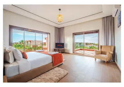 a bedroom with a bed and a chair and windows at Villa Dahlia Jacuzzi, Stove, Pool in Marrakech