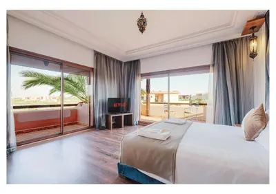a bedroom with a large bed and a balcony at Villa Camelia avec Jacuzzi, Cuisinière, Piscine in Marrakech