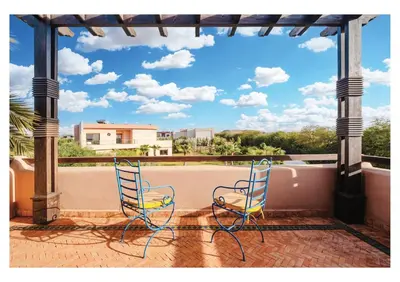 two blue chairs sitting on a balcony with a view at Villa Camelia avec Jacuzzi, Cuisinière, Piscine in Marrakech