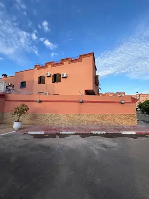 a orange building with a brick wall in a parking lot at Villa Ground Floor Rent Apt in Marrakech