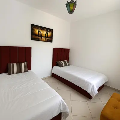 a bedroom with two beds and a chair in it at Appartement Moderne & Climatisé in Marrakech