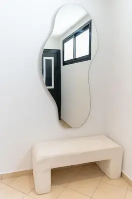 a mirror on a white wall next to a bench at Appartement élégant avec jacuzzi à deux pas de Guéliz in Marrakech