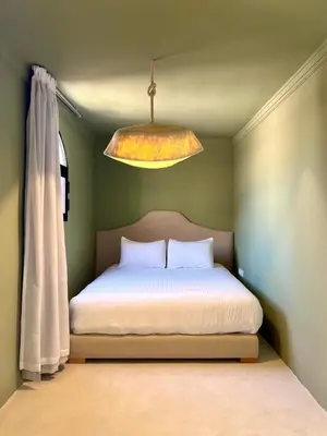 a bed in a green room with a light at Riad Roseli in Marrakech