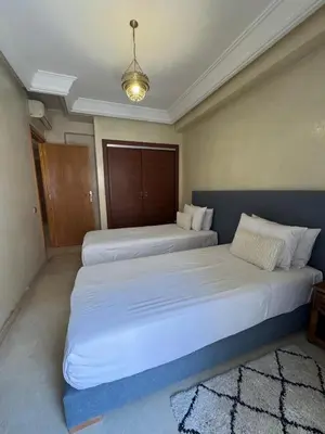 two beds in a room with a large bed at Sofia Palmeraie Appartement in Marrakech