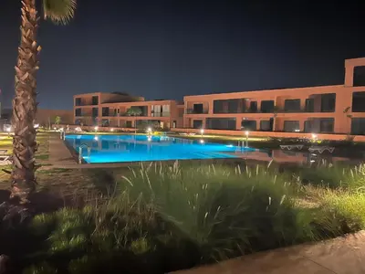 a building with a swimming pool at night at Noria Golf Marrakech in Marrakech