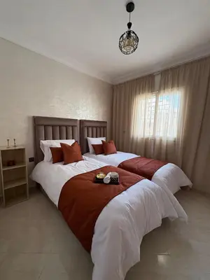 a bedroom with two beds with white and red pillows at Charmant appartement familial in Marrakech