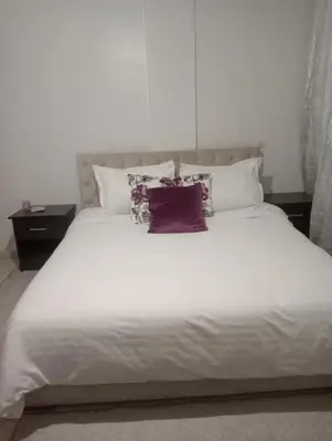 a large bed with white sheets and pillows at Appartement cosy in Marrakech