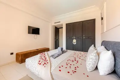 a bedroom with a bed with red flowers on it at Confort et style en pleins centre de Hivernage in Marrakech