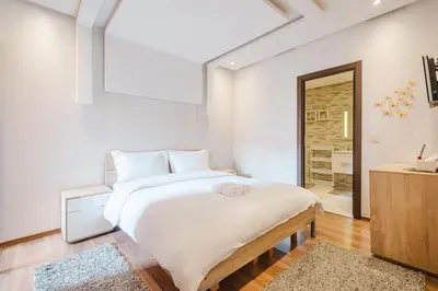 a white bedroom with a large bed and a bathroom at Luxe 2-Bedroom with Pool in Marrakech in Marrakech