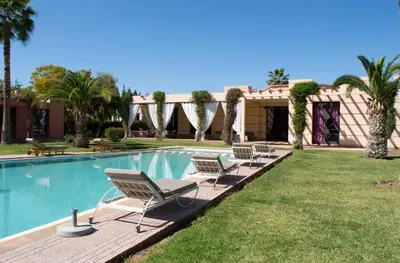 a swimming pool with chairs and a house at Domaine Marradise in Marrakech