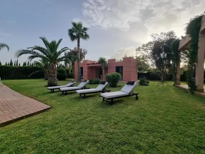 a row of benches sitting on a lawn with palm trees at Domaine Marradise in Marrakech
