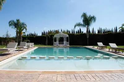 a swimming pool with chairs and a gazebo at Domaine Marradise in Marrakech